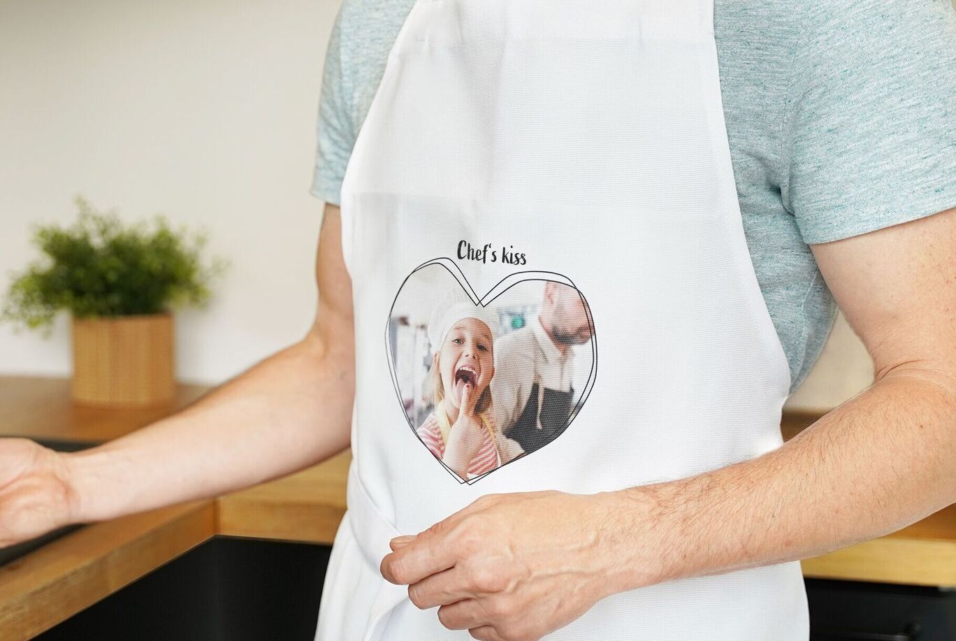 A chef wearing an apron with a heart design and a picture.