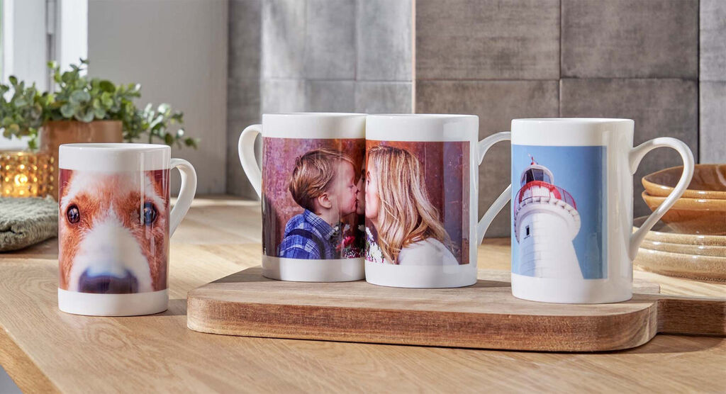Three personalized mugs with photos of loved ones on a wooden board.