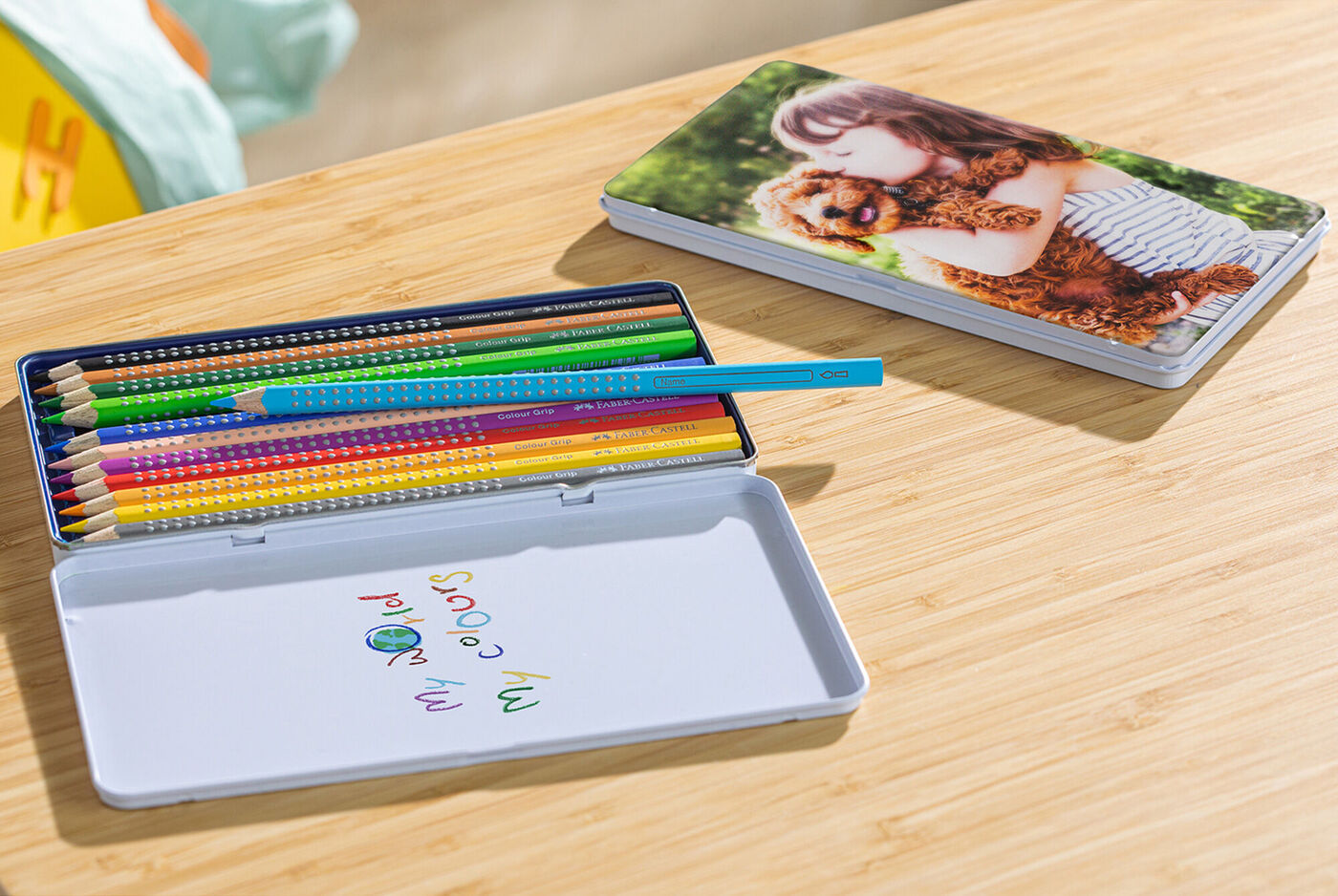 Colored pencils in a box and a photo book on a table.