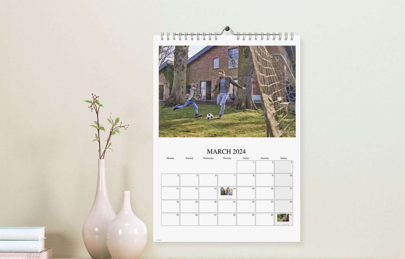 A cheerful child playing in the garden with a soccer ball in the CEWE photo calendar.