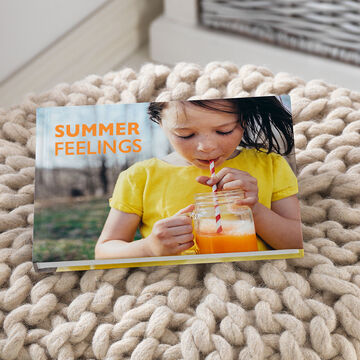 An open photo book titled 'Summer Feelings'. A person enjoys a drink and smiles outdoors.