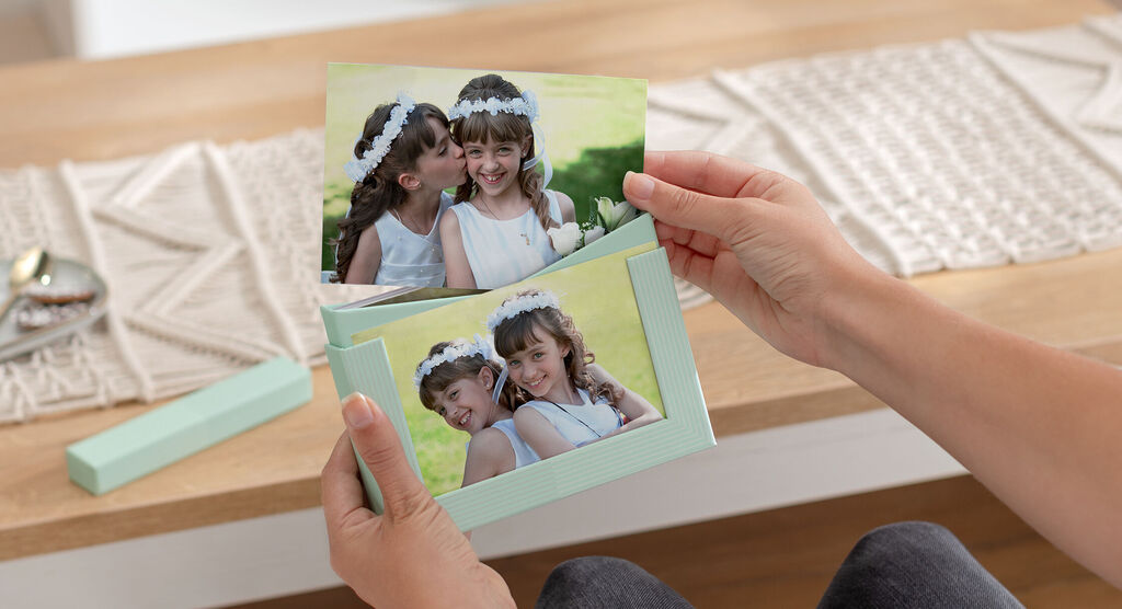 Two girls holding pictures with flower crowns at a wooden table.