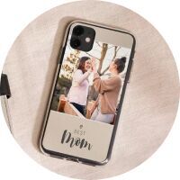 Two women laugh and enjoy a shared moment while holding a smartphone with a photo saying 'best mom'.
