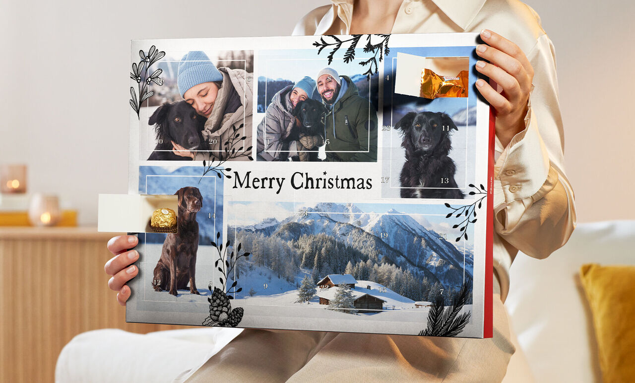 A person holds a creative photo book with Christmas motifs in their hands.