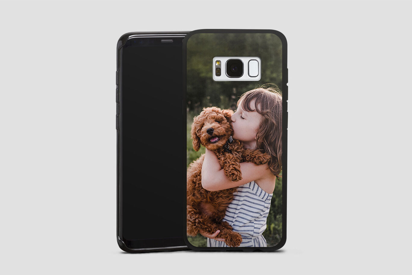 A happy child holds a dog in their arms and smiles happily.
