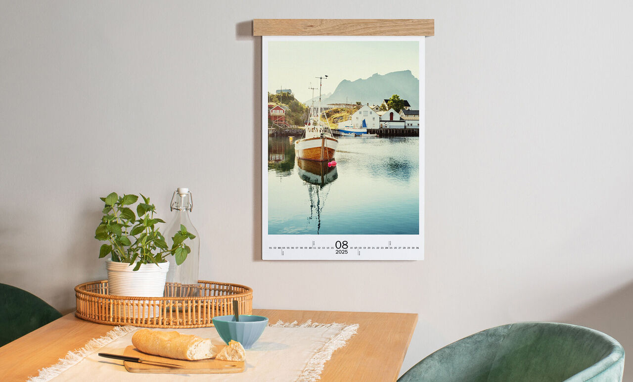 A stunning image of a calendar with a boat on calm water. The calendar hangs on the wall and shows August.