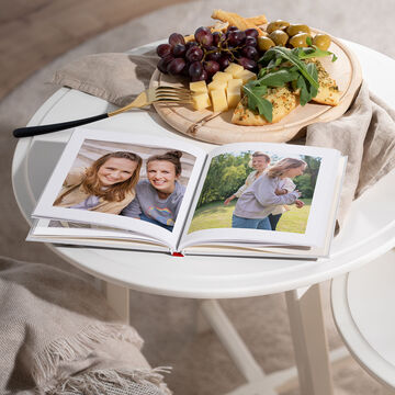 Open photo book with family photos and a platter of grapes, cheese, and olives on the table.
