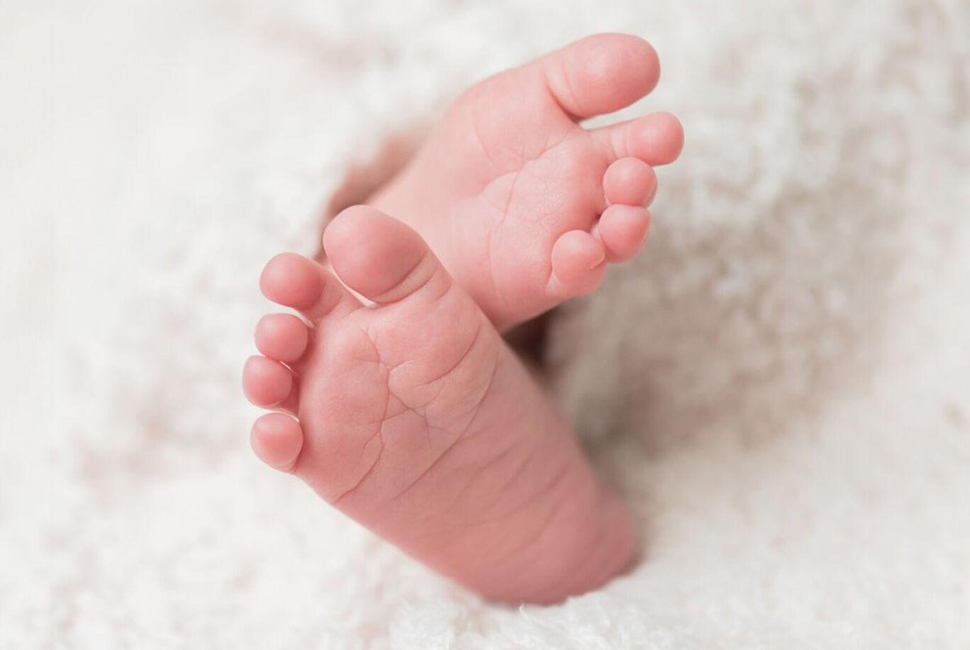 Delicate baby feet under a cozy blanket