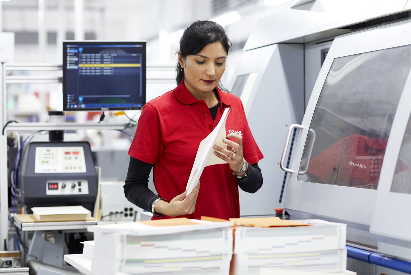 An employee checking printed materials in a modern printing house to ensure quality.