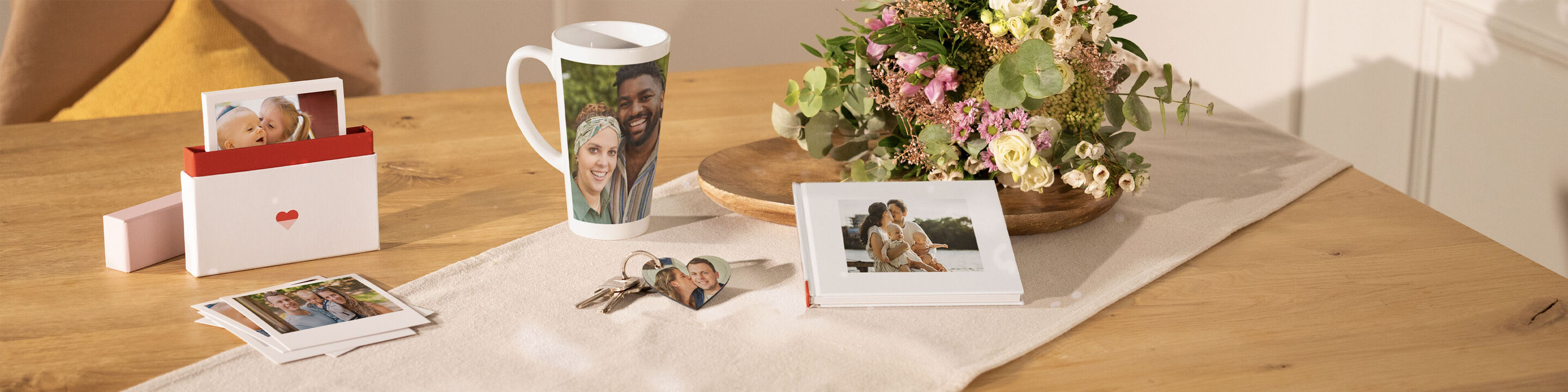 A lovingly designed coffee cup, photos, keys, and a flower arrangement on a table. Perfect gifts for loved ones.