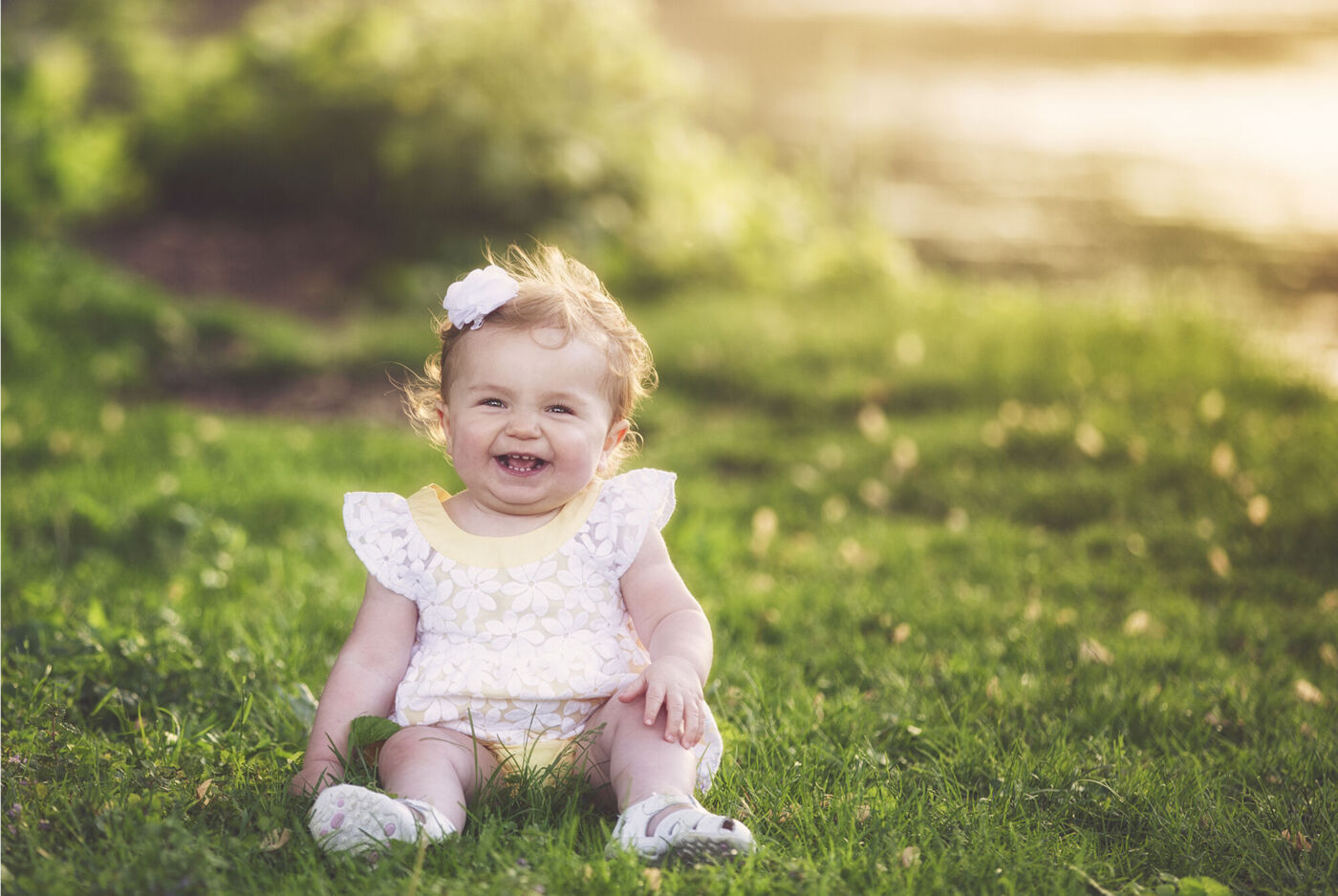 A small child happily sitting on the meadow surrounded by nature.