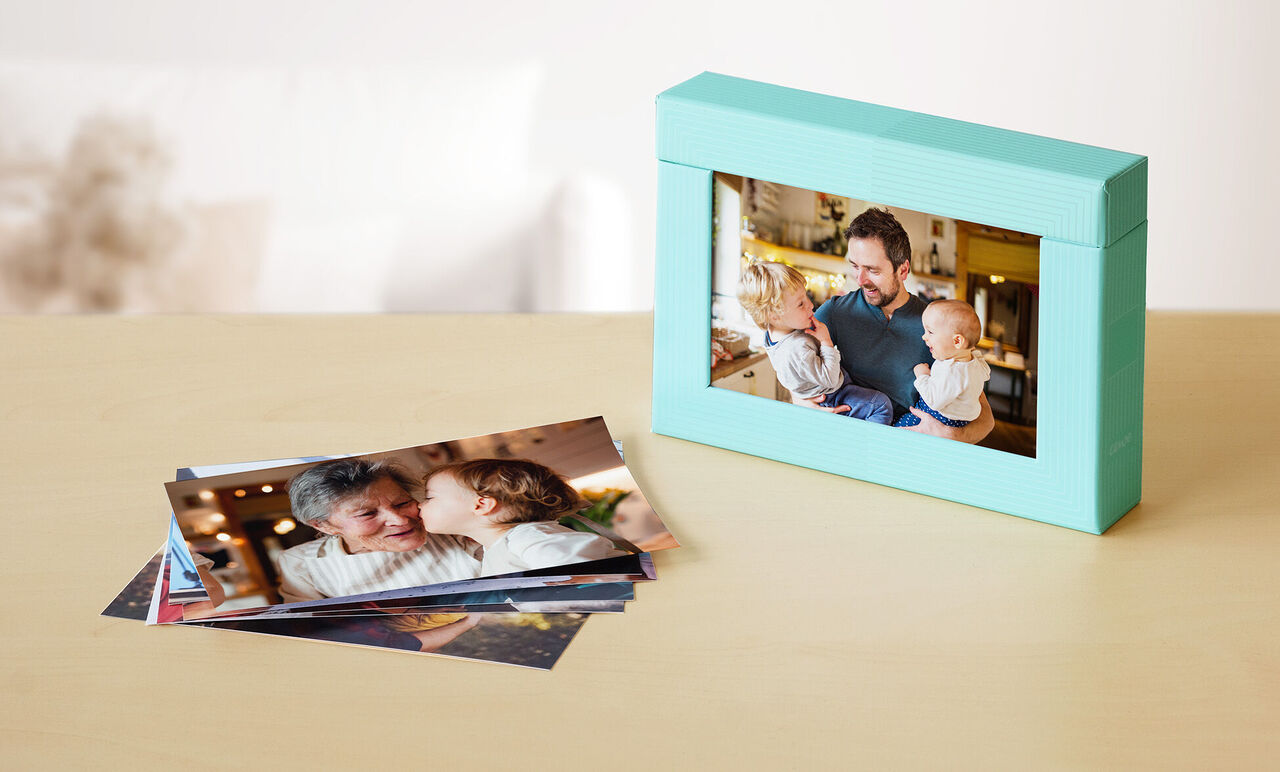 A lovingly designed mint green picture frame surrounded by printed photos showing joy and connection.