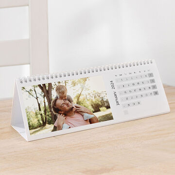 A family calendar for 2024 shows a man with a child on his back outdoors.
