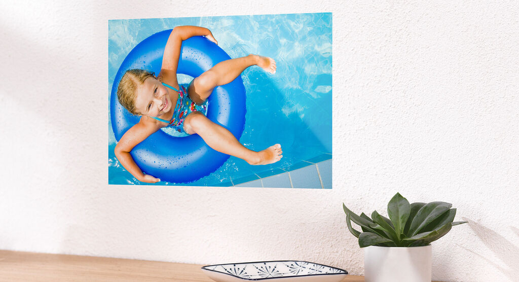 A happy girl sits in a blue swimming ring in the water enjoying summer.