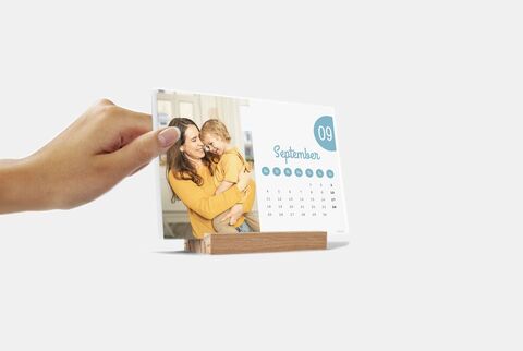 A person holds a CEWE photo calendar with a September sheet.