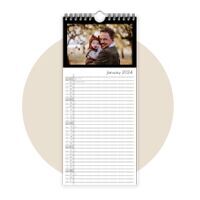 A joyful father holds his child in his arms while they stand outdoors. In the background, trees and bright light create a warm atmosphere. It is a CEWE photo calendar.