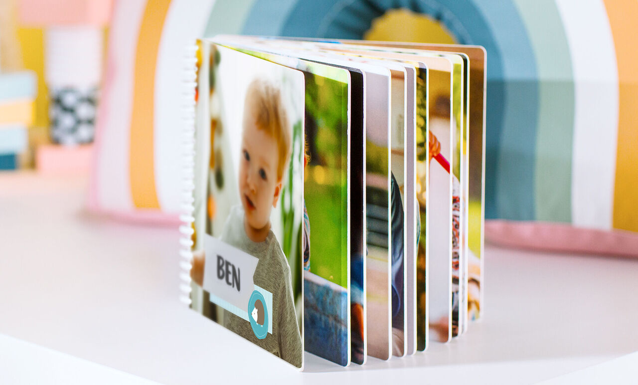 A friendly designed CEWE PHOTO BOOK with colorful photos and a name tag.