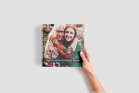 A hand holding a lovingly designed photo book for the 60th birthday.