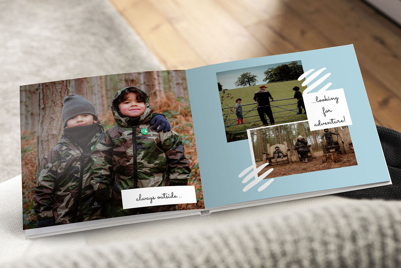Two children in camouflage jackets in the woods with a photo book showing adventures