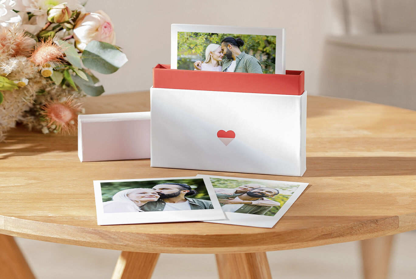 An elegant photo package with two photos and flower decorations on a wooden table.