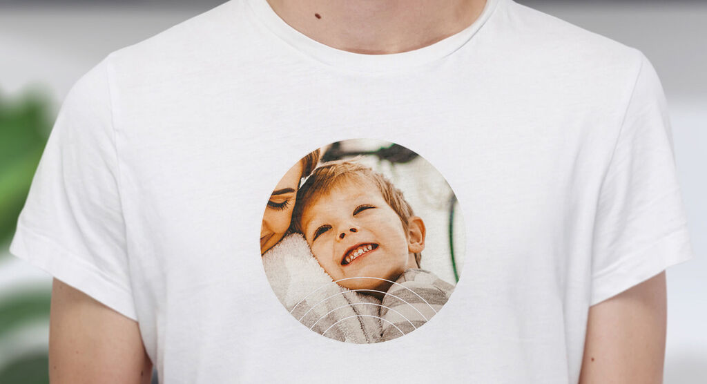 A person wearing a white T-shirt with a round print showing a loving scene of two happy people together.
