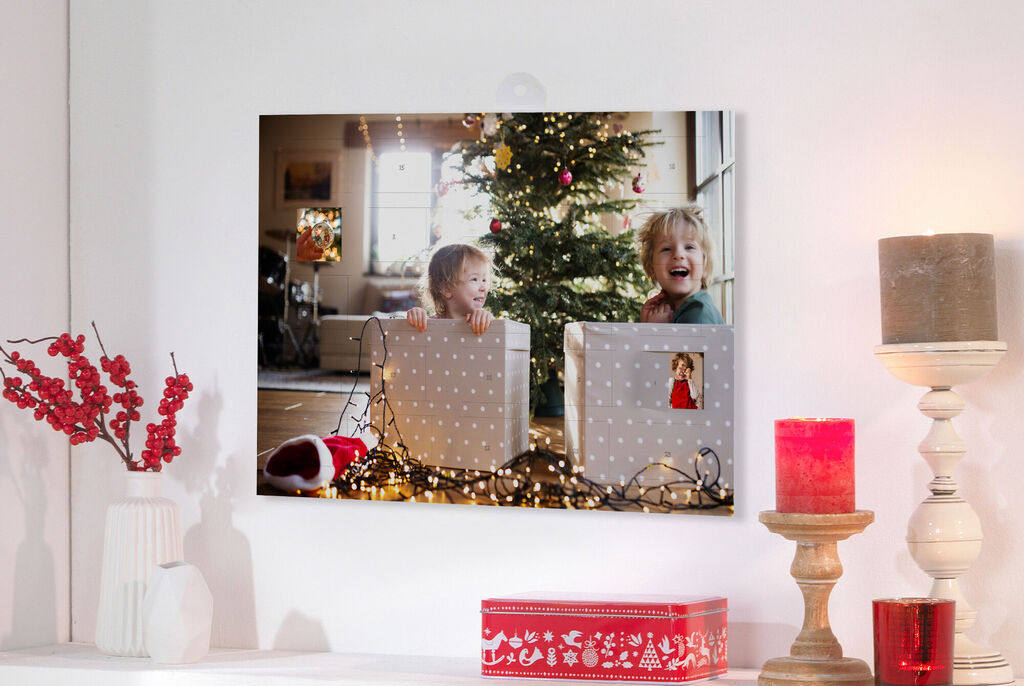 Two children in Christmas decorations hold gifts in front of a decorated Christmas tree