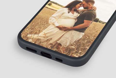 Pregnant woman and man embrace in a golden field.