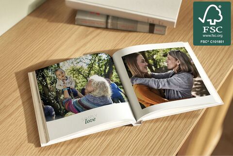 An open photo book on a wooden shelf shows loving moments of family and friends in nature.