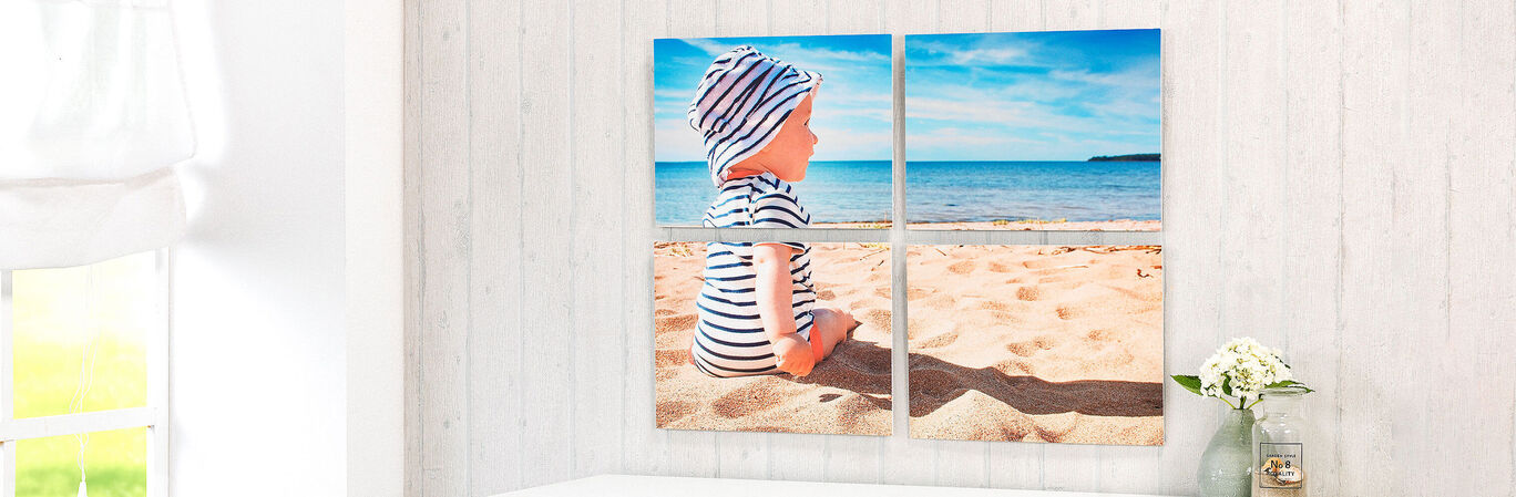 Boy in striped hat sitting on beach sand, looking at the sea