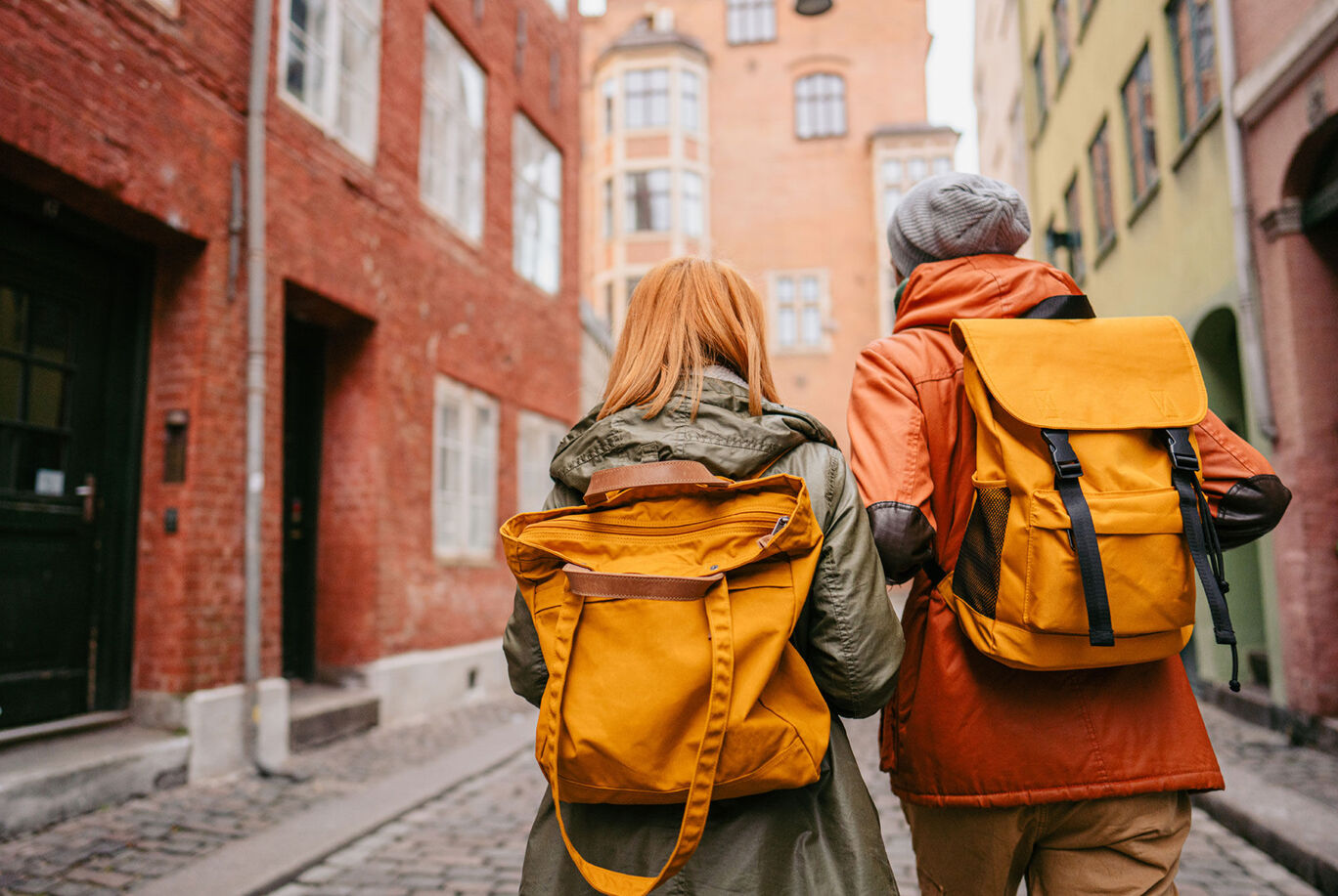 Two people with backpacks stroll through a picturesque city street.