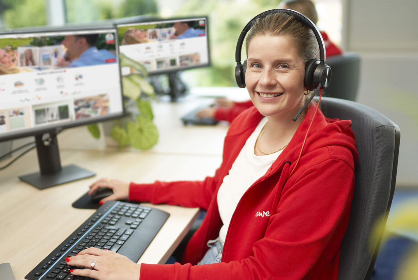 A CEWE employee works at a computer with a headset to assist customers.