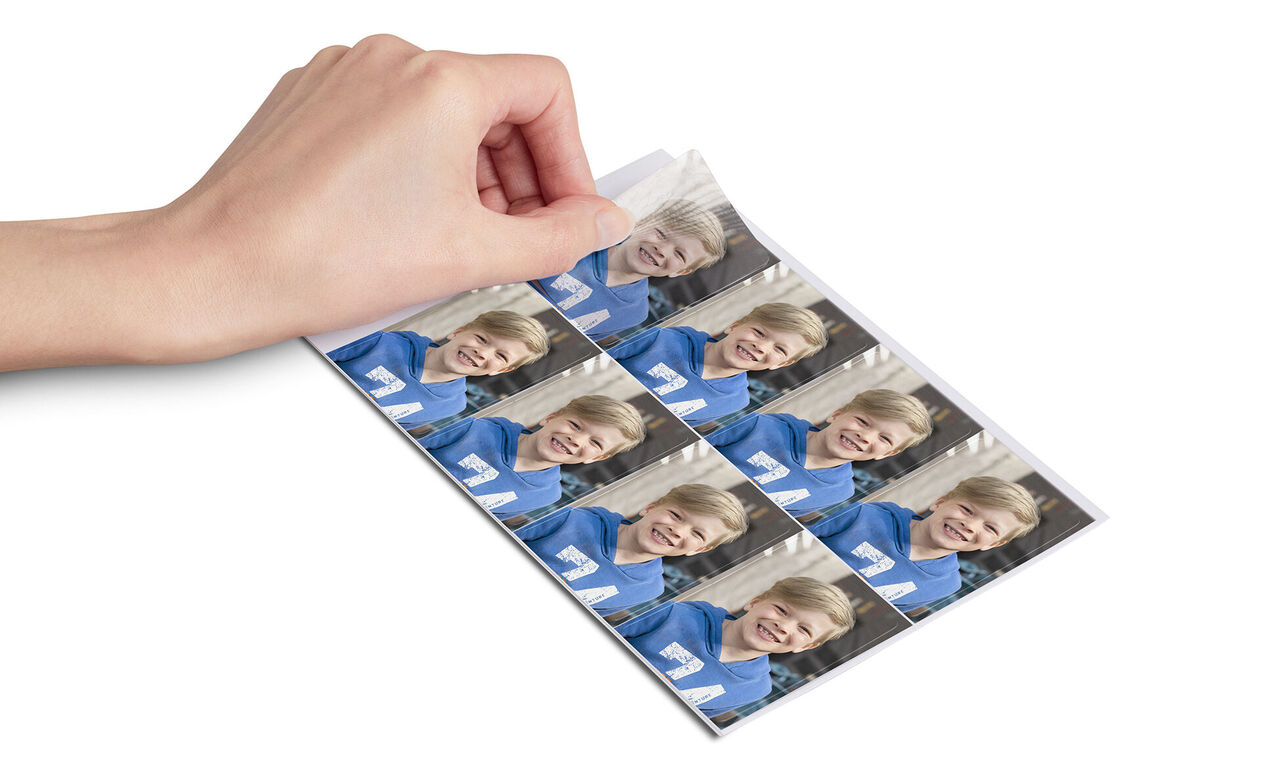 A hand shows photo prints of a boy in blue clothing.