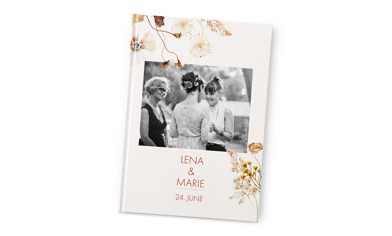 Two women stand next to each other, a moment of happiness with a floral motif on a photo book.