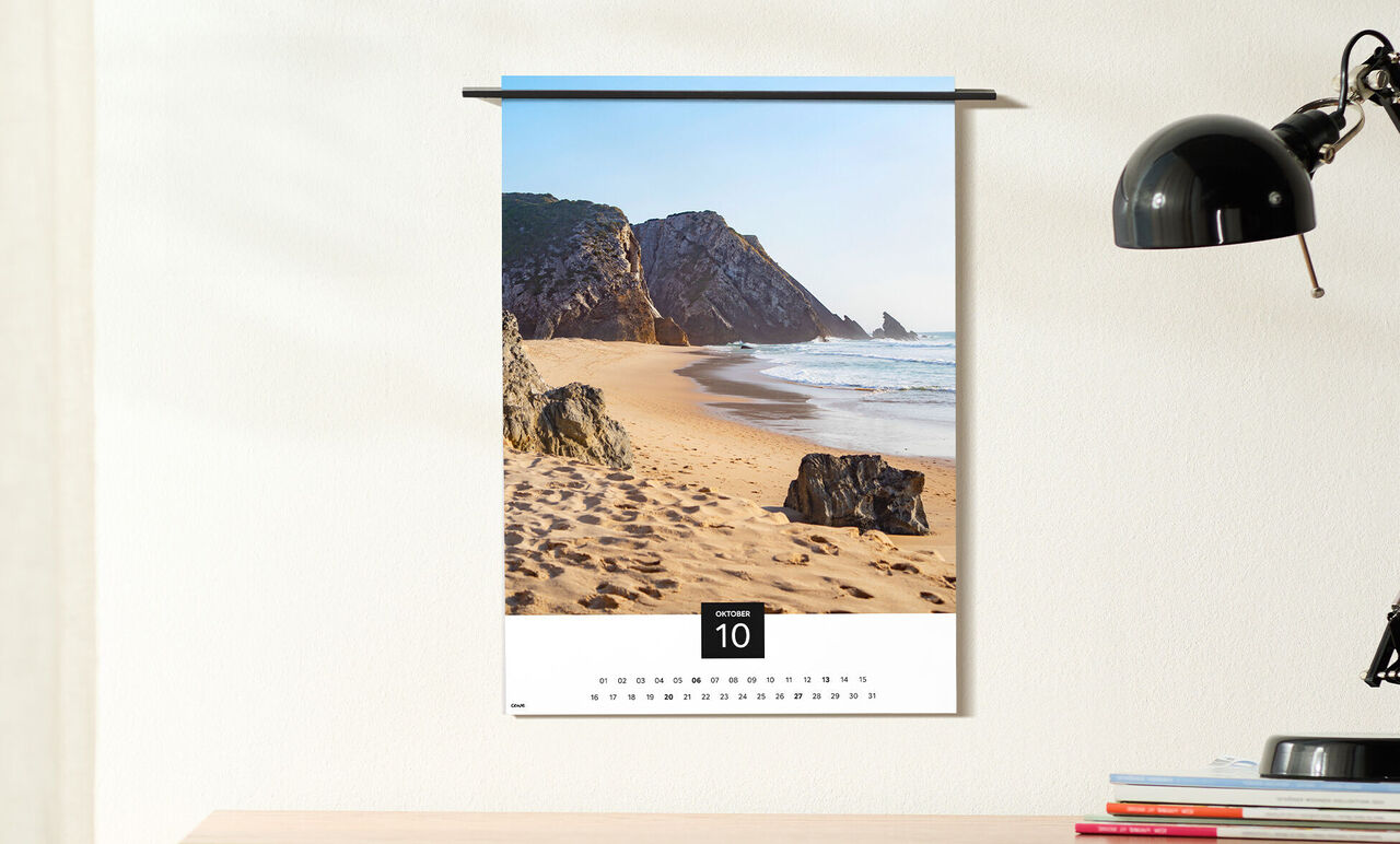 A beautiful beach with gentle waves and large rocks depicted in a wall calendar.