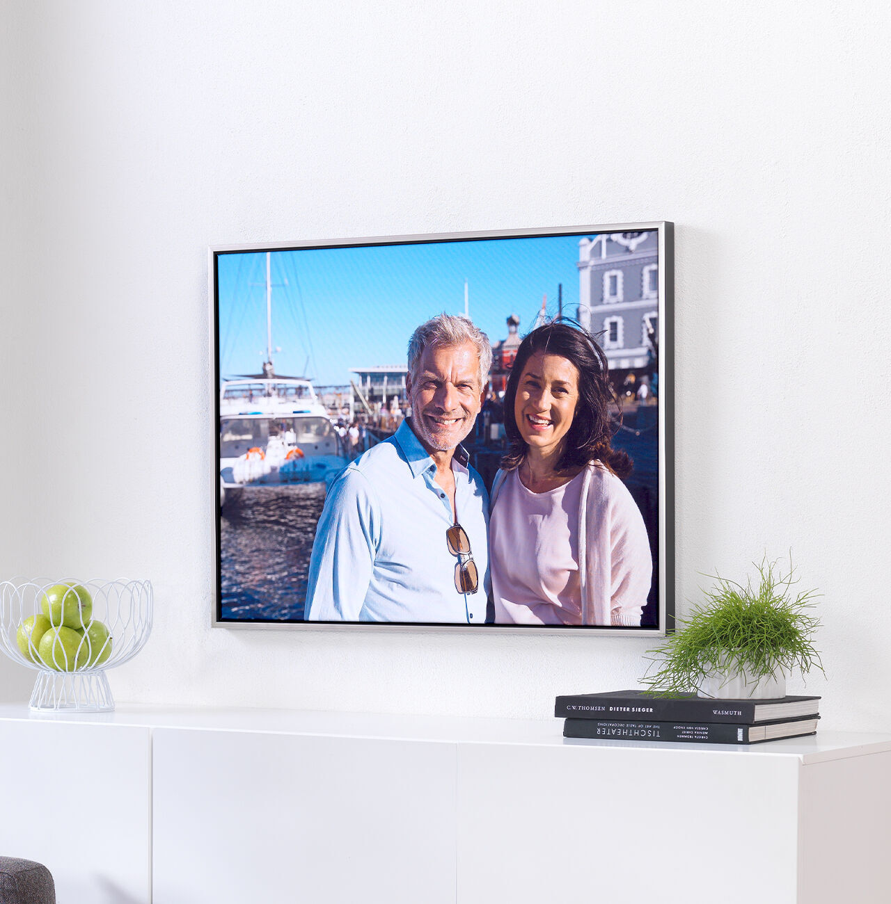 A happy couple poses at a harbor, surrounded by boats and beautiful architecture. They smile and enjoy the moment.