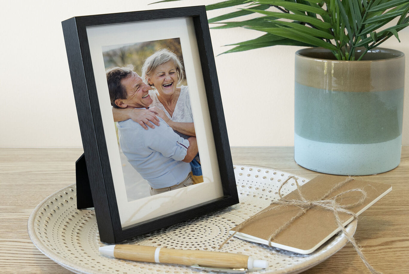 A lovely framed photo on a table, surrounded by a notebook and a pen.