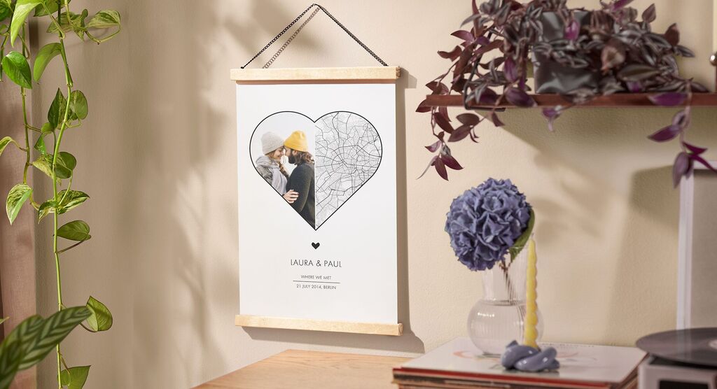 Two people kiss in a heart-shaped frame with a card in the background on a table.