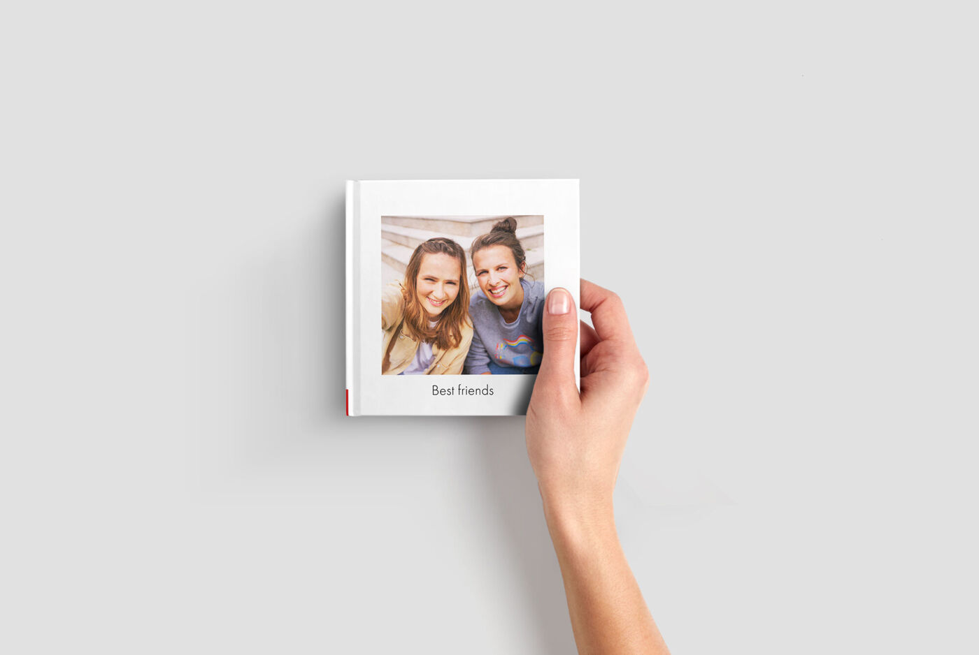 A CEWE PHOTO BOOK titled 'Best Friends' held in one hand.